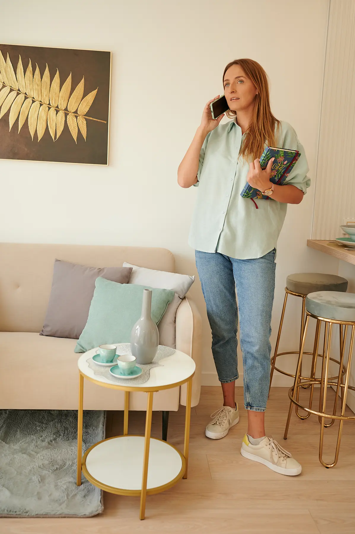 Kobieta stojąca przed kanapą i rozmawiająca przez telefon. Projektowanie wnętrz Olsztyn